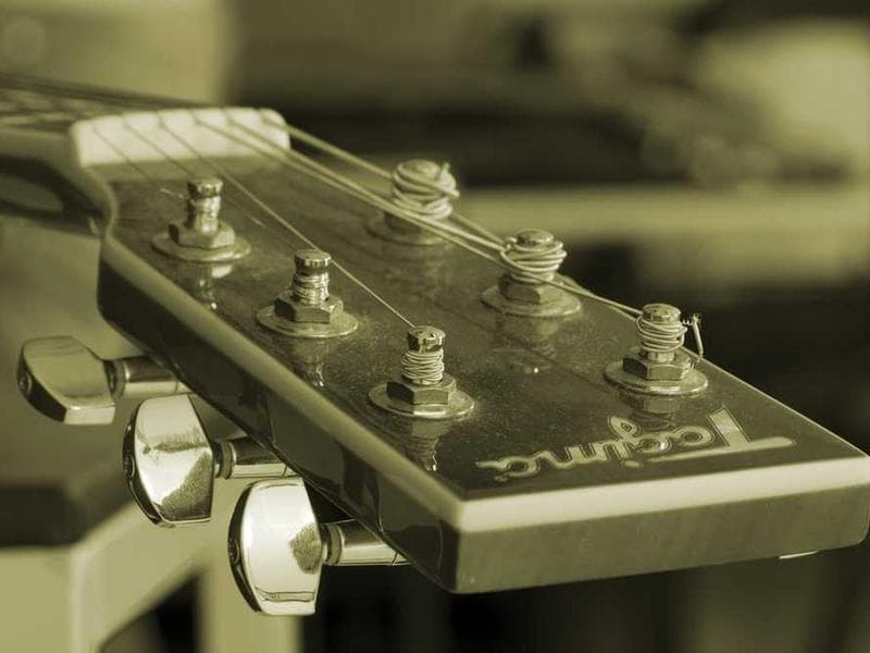 Vintage-toned close-up of guitar headstock with tuning pegs